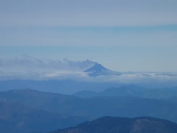 Fumar villarica volcán en una distancia por encima de las nubes —  Fotos de Stock