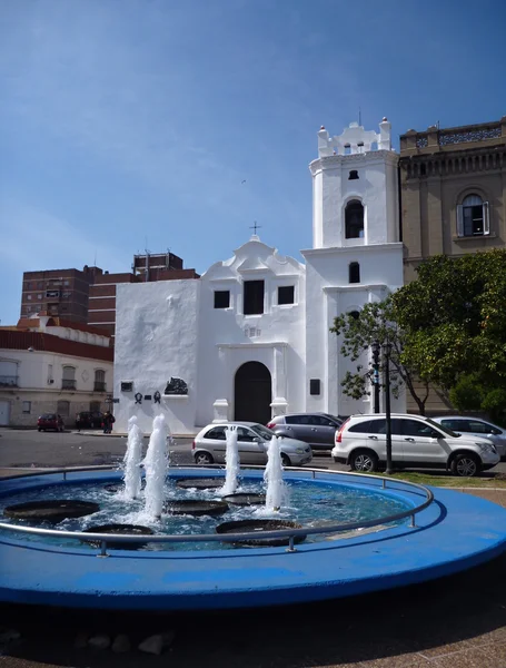 Fontaine ronde bleue devant une église blanche — Photo
