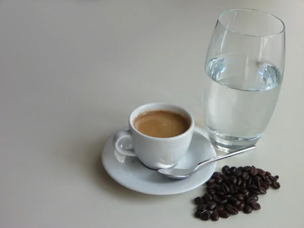 Xícara de café saboroso fresco com grãos de café e um copo de água — Fotografia de Stock