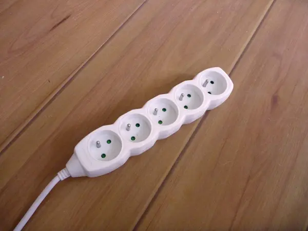 White miltu socket on a wooden floor — Stock Photo, Image