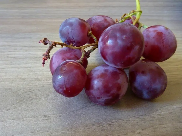 Bayas de uva roja fresca en una mesa de madera — Foto de Stock