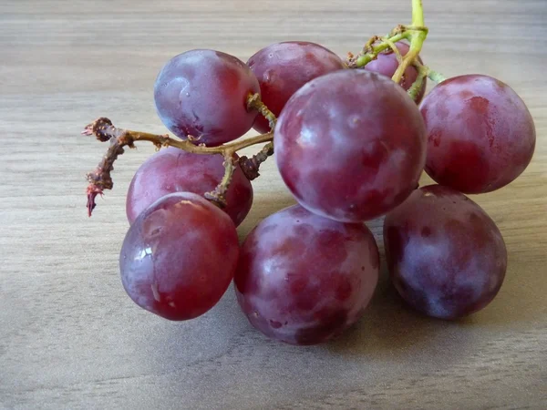 Bayas de uva roja fresca en una mesa de madera — Foto de Stock