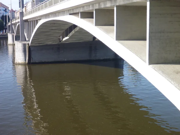 Concrete bridge arch reflected in river water — Stock Photo, Image