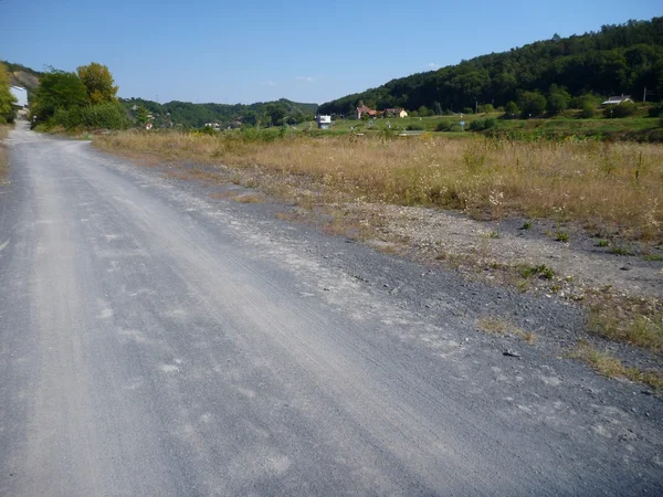 Leere Schotterstraße mit trockenem Gras — Stockfoto