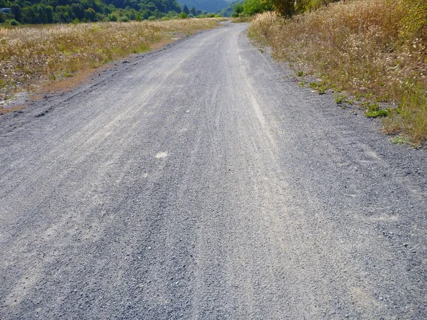 Пустая грунтовая дорога с сухой травой — стоковое фото