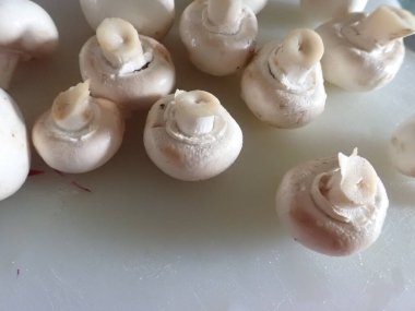 Mutfakta beyaz bir kesme tahtasıyla mantar kesiyorum.