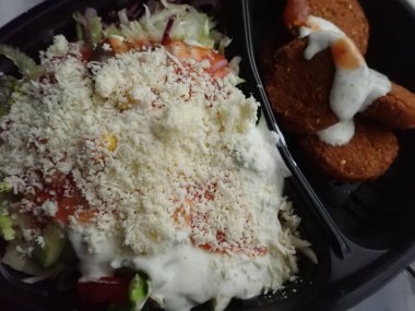 Sebze salatalı kızarmış falafel paket plastik tabakta.