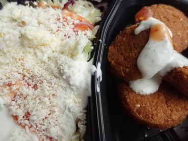 Sebze salatalı kızarmış falafel paket plastik tabakta.
