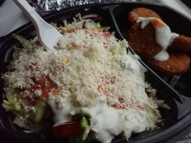 Sebze salatalı kızarmış falafel paket plastik tabakta.