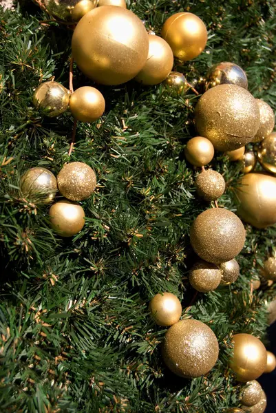 Golden christmas decoration at green branches — Stock Photo, Image