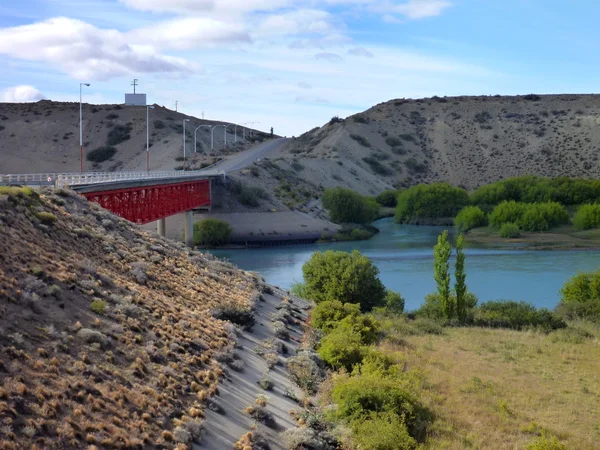 Patagonya'parlak mavi nehir üzerinde kırmızı köprü — Stok fotoğraf