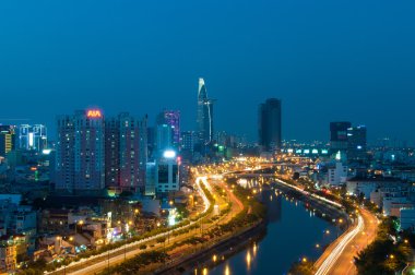Ho Chi Minh city Riverside cityscape gece görünümü ile Ben Nghe veya Tau Hu kanal ve calmet Köprüsü.