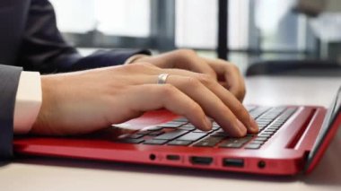 Ofisteki dizüstü bilgisayarda çalışan bir adam. Eller klavyede yazı yazıyor. Ofis işi.