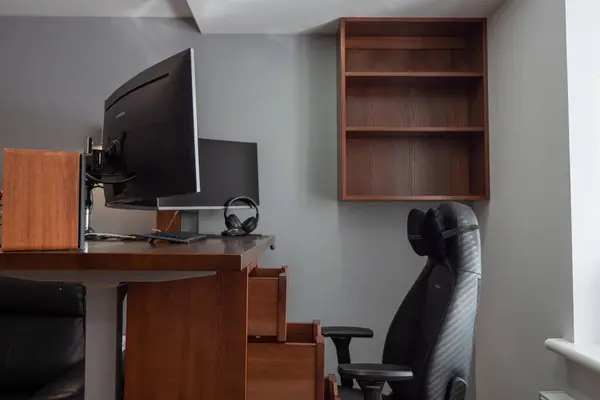 General view of home workplace of pro gamer with professional gaming setup on desktop. Modern powerful PC full RGB light inside, display with shooter game, armchair. Gaming studio of cyber sportsman