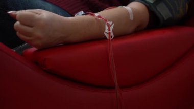 Bir adam kan nakli merkezinde kan bağışlarken yumruğunu sıkar..