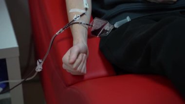 Bir adam kan nakli merkezinde kan bağışlarken yumruğunu sıkar..