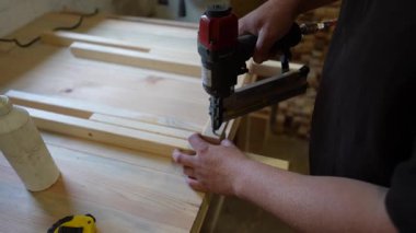 Bir marangozun tahta parçasını çivi tabancasıyla çivilediği yakın plan görüntüsü..