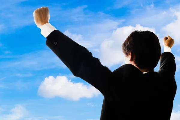 Hombre de negocios feliz con los brazos levantados bajo el cielo azul.Indica — Foto de Stock