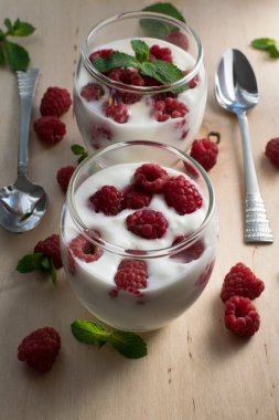 ahşap arka plan üzerinde iki kişilik ev yapımı yoğurt ahududu, pudra şekeri ve nane yaprakları