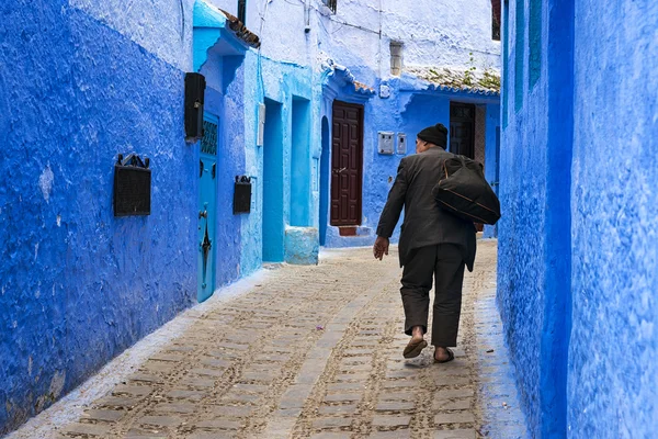 Homme marchant dans une rue de la ville de Chefchaouen au Maroc . — Photo