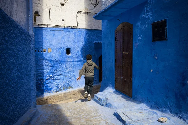 Enfant courant dans une rue de la ville de Chefchaouen au Maroc . — Photo