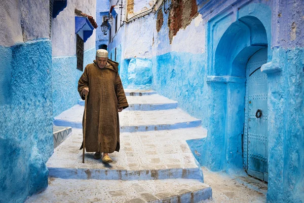 Old man walking in a street of the town of Chefchaouen in Morocco.