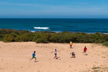 El Jadida, Fas - 16 Nisan 2016: Fas 'ın Atlantik kıyısındaki El Jadida kenti yakınlarında bir plajda futbol (futbol) oynayan bir grup genç erkek.