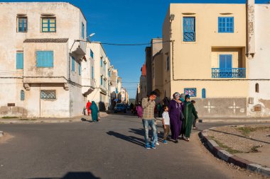 Essaouira, Fas - 15 Nisan 2016: Essaouira şehrinin bir yerleşim bölgesinde sokak manzarası, insanların harap ve renkli binalarda yürüdüğü.