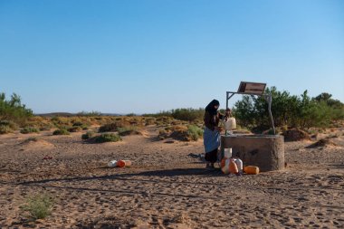 Erg Chebbi, Fas - 12 Nisan 2016: Fas 'taki Erg Chebbi kuyusundan su toplayan berber kadın.