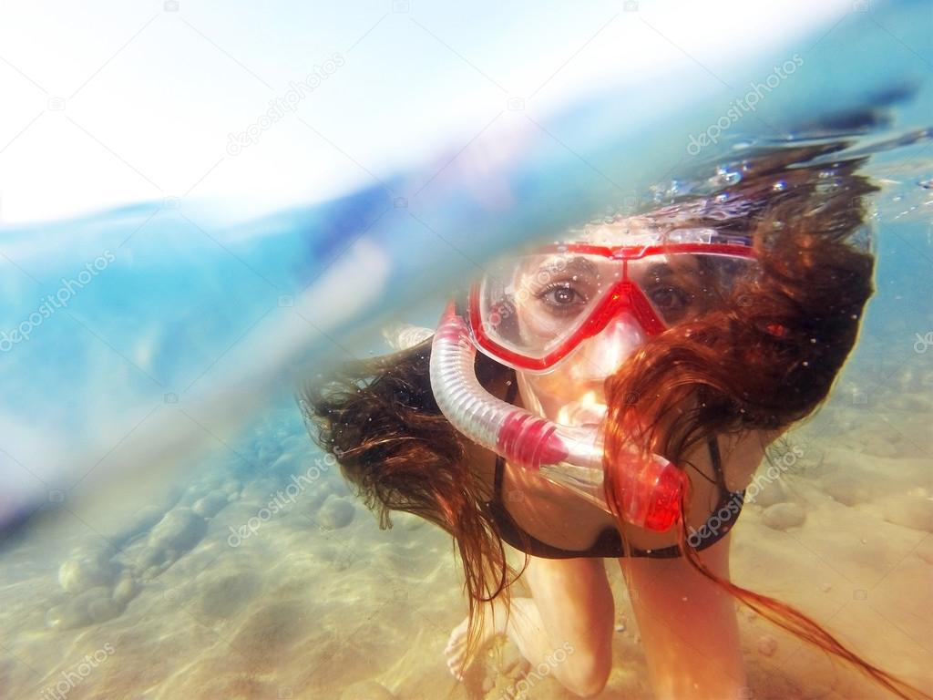 Woman with mask snorkeling in amazing clear water