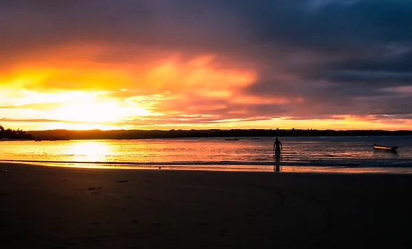 Bir adam ve bir tekne ile sahilde günbatımı