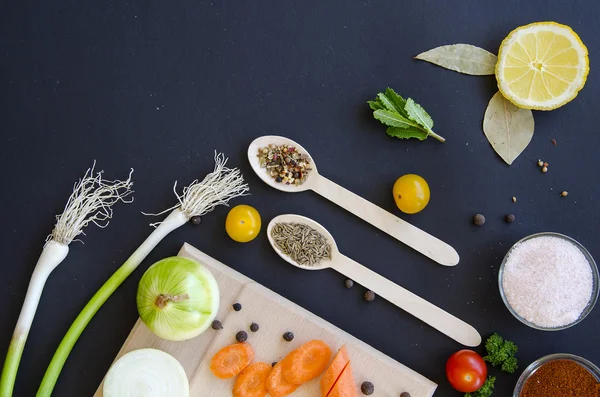 Ingrédients délicieux frais pour une cuisine saine ou la fabrication de salades sur fond noir foncé et planche à découper en bois — Photo