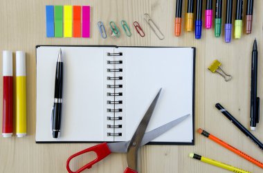 Ofis malzemeleri ahşap bir masa arka plan üzerinde döşeme. Üst te. Kalemler, makaslar, işaretler, çıkartmalar, yer imleri, gözlükler