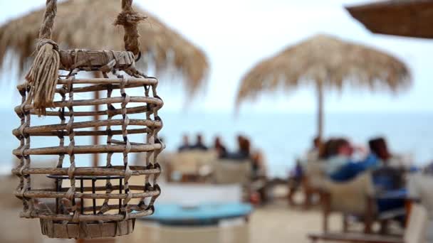 Άδειο λαμπτήρων σε ένα beach bar ή στο καφέ ταλαντεύεται στο ένα αεράκι της θάλασσας σε μια μαύρη θάλασσα παραθαλάσσιο. Θολή θάλασσα. HD. 1920 x 1080 — Αρχείο Βίντεο