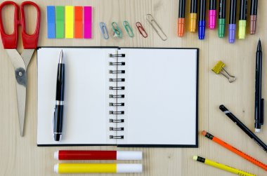 Ofis malzemeleri ahşap bir masa arka plan üzerinde döşeme. Üst te. Kalemler, makaslar, işaretler, çıkartmalar, yer imleri, gözlükler