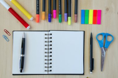 Ofis malzemeleri ahşap bir masa arka plan üzerinde döşeme. Üst te. Kalemler, makaslar, işaretler, çıkartmalar, yer imleri, gözlükler