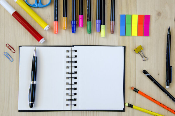 Office supplies laying on a wooden desk background.Top view. Pencils,scissors,markers,stickers,bookmarks,glasses