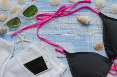 Yaz plaj deniz kavramı. Farklı aksesuarlar, kabuklar, deniz yıldızı, güneş gözlüğü, swimsuite ile mavi ahşap arka plan