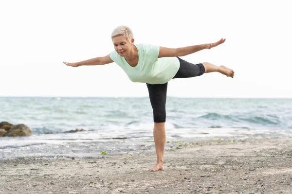 Mature woman trainer takes youga courses. Balance exercises. — Stock Photo, Image
