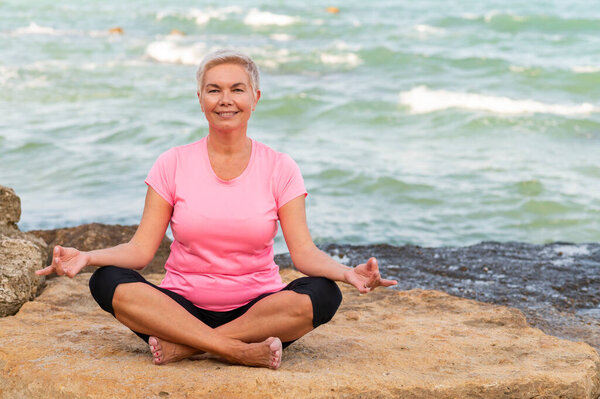 Sports mid age woman meditating at the beach and smiling