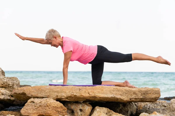 Pilates yapan yaşlı bir kadının yan görünüm portresi.