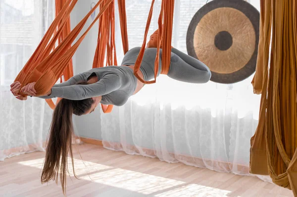 Hermosa mujer deportiva practica yoga con mosca en una hamaca, equilibrándose y estirándose hacia atrás —  Fotos de Stock