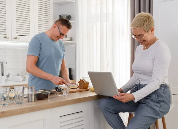 Senior Ehemann kocht Frühstück für seine Frau. Glückliches Paar zu Hause. — Stockfoto