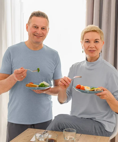 Fröhliches Seniorenpaar beim gemeinsamen gesunden Frühstück. Glückliches Leben der Rentner. — Stockfoto