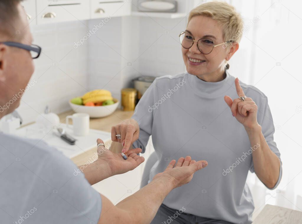Portrait of middle aged couple taking pills together before dinner. Healthcare for elderly people