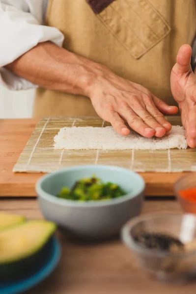 Chefe mestre Sushi mãos close-up faz rolos de sushi com arroz — Fotografia de Stock