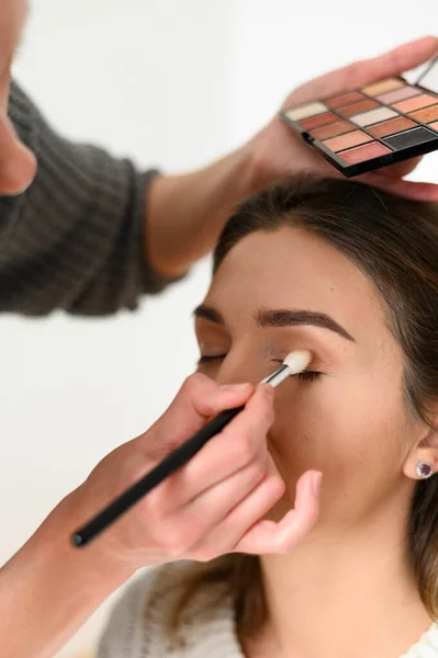 Maskenbildnerin, die eine lächelnde junge Frau professionell schminkt. Make-up-Unterricht — Stockfoto