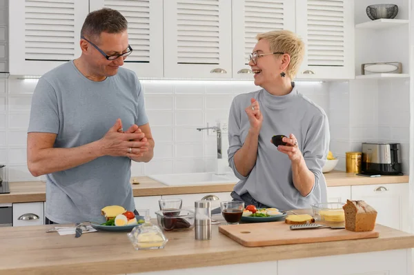 Lächelndes Seniorenpaar kocht gesunde Lebensmittel mit gesundem frischem Gemüse in der Küche — Stockfoto