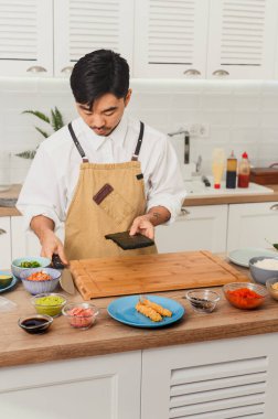 Usta şef, Nori ile suşi sarması yapıyor. Asyalı şef mutfakta, yemek teslimatı.