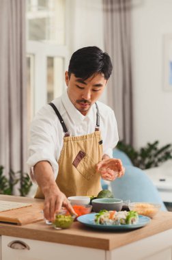 Somon, salatalık, avokado, krem peynir, Asyalı Şef 'le kırmızı masago havyarlı rulo suşi yapma süreci.